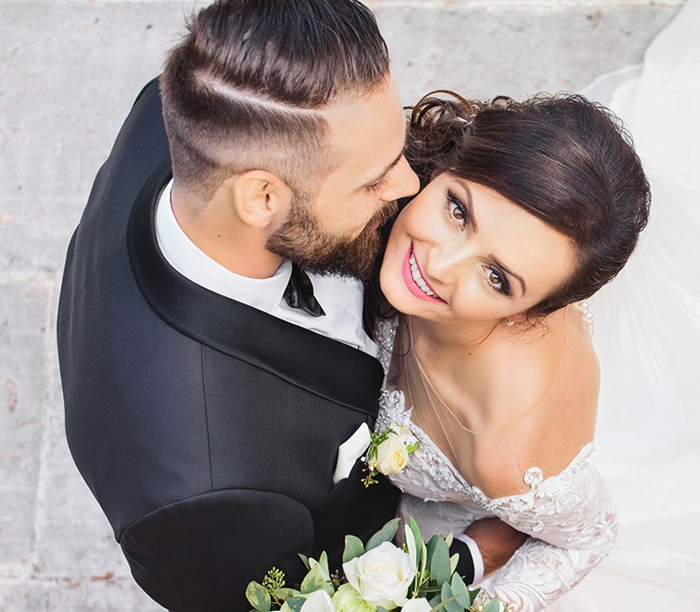 wedding couple in embrace with smiling woman looking up to camera and man looking at her